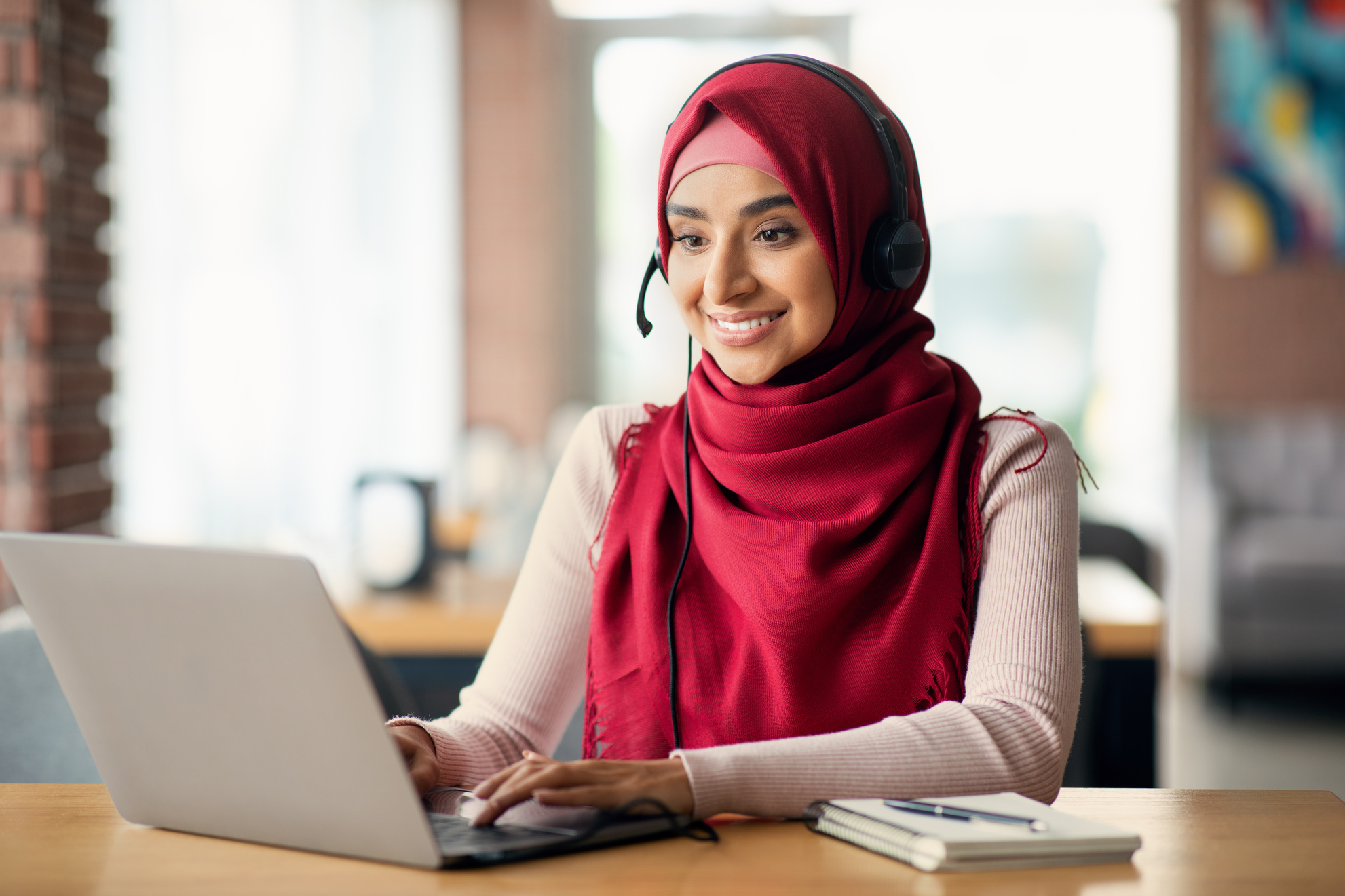 Joyful muslim woman attending online course, cafe interior, copy space
